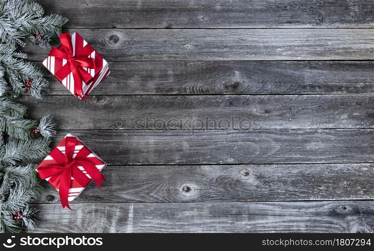 Frosted snow covered evergreen branches with red giftboxes ornaments on faded wooden planks for a merry Christmas or happy New Year holiday celebration concept