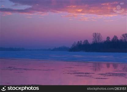 Frosty dawn on the Bug river, purple highlighted sky and reflection in water. January in Poland. Horizontal view