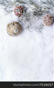 Frosty winter fir branches with vintage Christmas bauble and cones on snow background. Copy space. Happy holidays