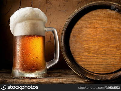 Frothy beer and wooden barrel in clay cellar