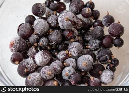 Frozen berries on a white background in a glass bowl.