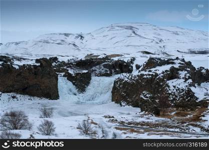 Frozen Hjalparfoss waterfall on a cloudy morning, winter in Iceland, Europe