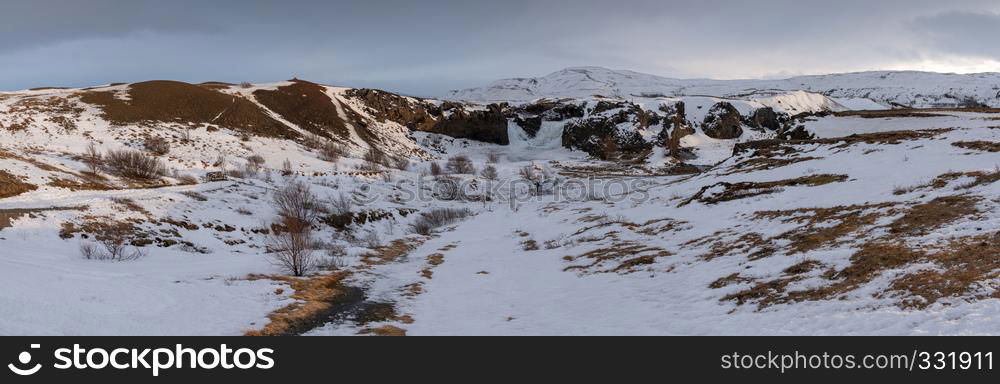 Frozen Hjalparfoss waterfall on a cloudy morning, winter in Iceland, Europe