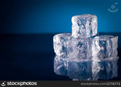 Frozen ice cubes on blue background with reflection
