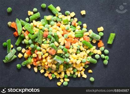 Frozen mixed vegetables (green bean, pea, carrot, sweet corn) photographed overhead on slate with natural light (Selective Focus, Focus on the vegetables on the top). Frozen Mixed Vegetables