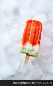 Frozen natural vanilla watermelon smoothies on a stick on ice cubes. Ice lolly. Top view. Ice lolly with vanilla smoothie on ice cubes. Homemade cold healthy dessert. Top view