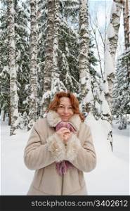 Frozen red-haired woman on winters day in forest.