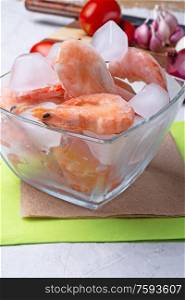 frozen shrimps in bowl with vegetables on white table. close up