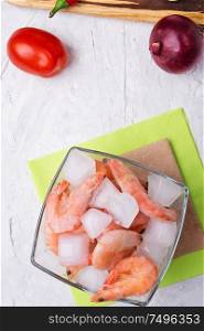 frozen shrimps with vegetables on white table. flat lay