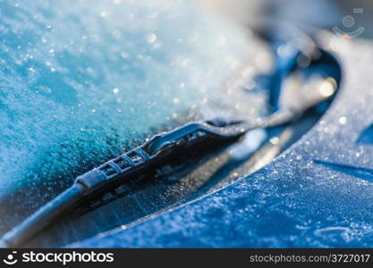 Frozen windshield, cold weather, sunlight on backlight, focus on foreground