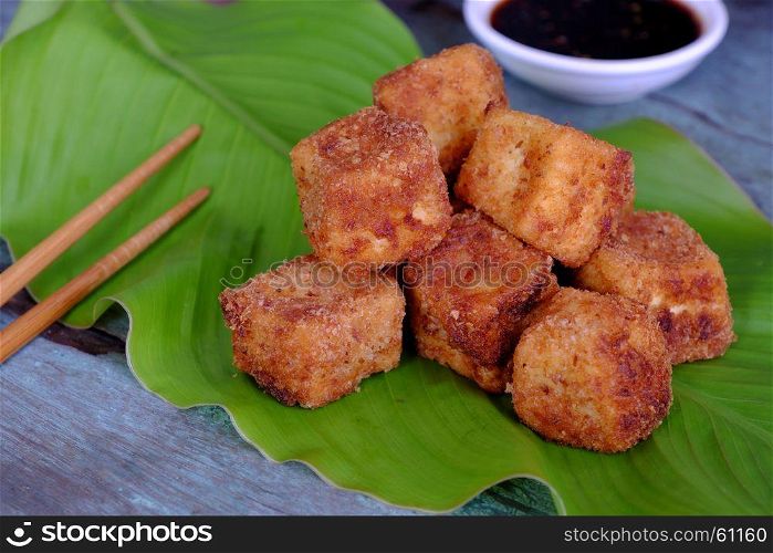 Frugal vegetarian food from Vietnamese cuisine, fried tofu with spice power, cover with crispy flour, homemade food on green leaf background, soya sauce for vegan