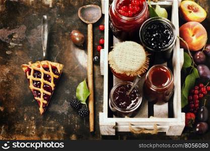 Fruit and berry jam and pieces of fruit tart on a rustic background