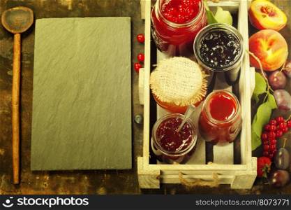 Fruit and berry jam with ingredients on a rustic background