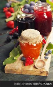 Fruit and berry jam with ingredients on a wooden background