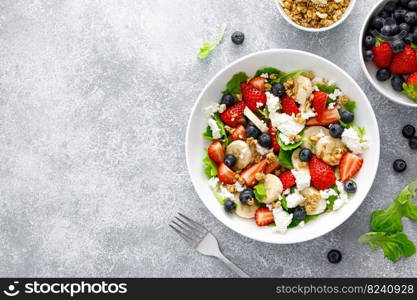 Fruit and berry salad with fresh strawberry, blueberry, banana, cottage cheese and granola with almond. Healthy food, diet breakfast