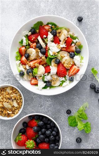 Fruit and berry salad with fresh strawberry, blueberry, banana, cottage cheese and granola with almond. Healthy food, diet breakfast