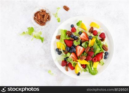 Fruit and berry salad with strawberry, blueberry, raspberry, mango and pecan nuts. Healthy food, diet. Top view