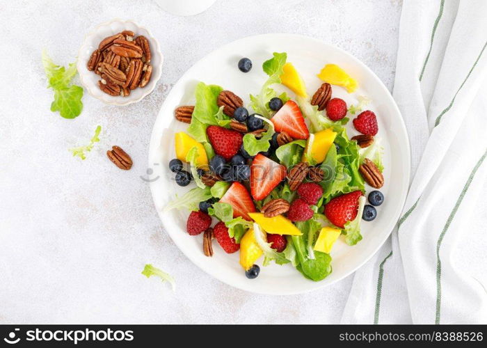 Fruit and berry salad with strawberry, blueberry, raspberry, mango and pecan nuts. Healthy food, diet. Top view