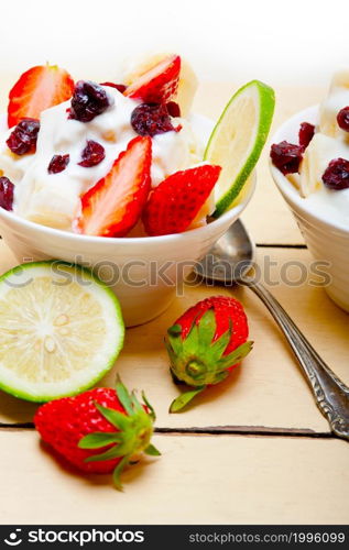 fruit and yogurt salad healthy breakfast over white wood table