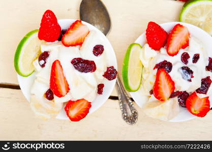 fruit and yogurt salad healthy breakfast over white wood table