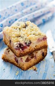 Fruit cake with streusel over light blue background, selective focus