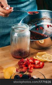 Fruit canning at home. Woman pouring cooked jam into sterile jars. Fruit preservation.. Pouring Fruit Jam into a Jar, Canning at Home.