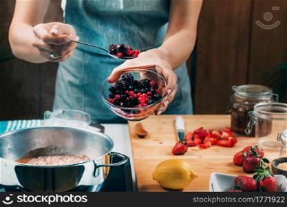 Fruit canning preservation. Woman cooking fruits and making homemade jam.. Woman Cooking Fruits and Making Homemade Jam.