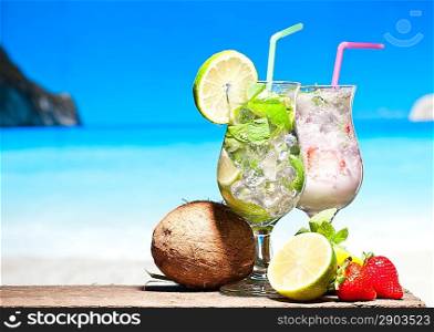 Fruit cocktail and Mojito with blue beach on background