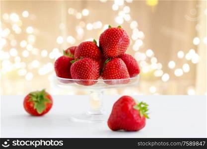 fruit, food and berries concept - strawberries on glass stand over lights on beige background. strawberries on glass stand over white background