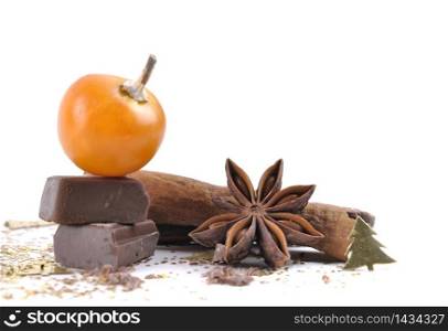 fruit of physalis on piece of chocolate with anise, cinnamon and cookies on white background
