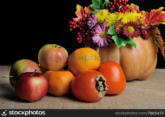 fruit on the table with flowers in a vase pumpkin