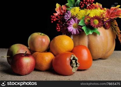 fruit on the table with flowers in a vase pumpkin