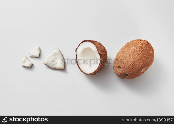 Fruit pattern from different parts of fresh ripe natural organic exotic coconuts fruit on a light grey background with copy space. Vegetarian concept.. Set from fresh ripe natural organic coconut fruits on a light grey background.