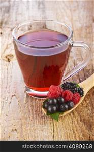 Fruit red tea with wild berries in wooden spoon on brown wooden table