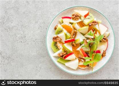 Fruit salad of fresh sweet apple, pear, tangerine and walnuts. Healthy vegetarian food
