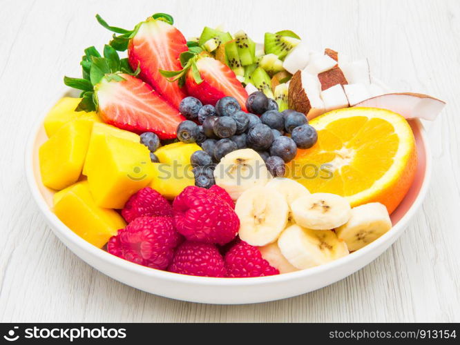 fruit salad with fresh berries, orange, coconut, mango, and sliced of banana
