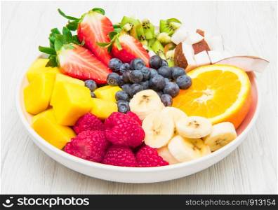 fruit salad with fresh berries, orange, coconut, mango, and sliced of banana