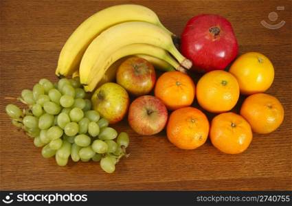 Fruit selection. Bananas, grapes, oranges, apples, tangerines and a red pomegranate.