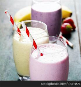 Fruit smoothies with black currant, strawberry and banana on wooden background