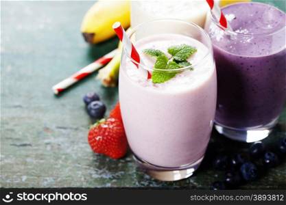 Fruit smoothies with black currant, strawberry and banana on wooden background