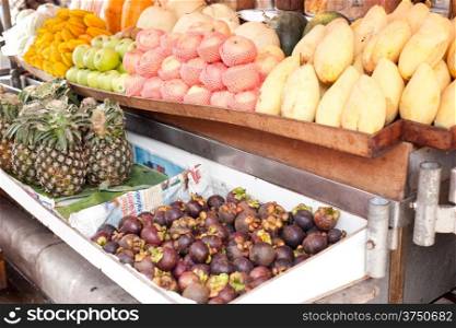 Fruit stalls in the market, pineapple, mango, apple, available for purchase.