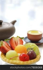 Fruit tart and Chinese tea with blue blur background