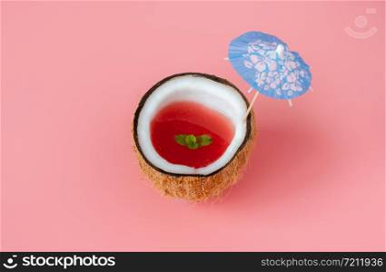 Fruit tropical with spring summer holiday & vacation background concept.Arrangement watermelon juice in sliced coconut & umbrella beach on modern pink paper.Minimal style with pastel tone design.