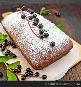 Fruitcake bird cherry with berries on a paper on the background of the dark wooden board