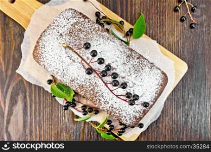 Fruitcake bird cherry with berries on a paper on the background of the wooden board top