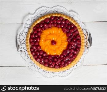 fruitcake with cherries and tangerines on white wood. fruitcake with cherries and tangerines on white wood.