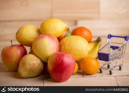 fruits and a shopping cart on a wooden table, studio picture