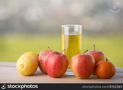 fruits and apple juice on a wooden table, outdoor