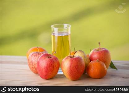 fruits and apple juice on a wooden table, outdoor