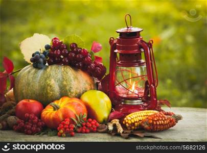 Fruits and nuts, pumpkins on the table outdoor and kerosene lamp - cozy autumn